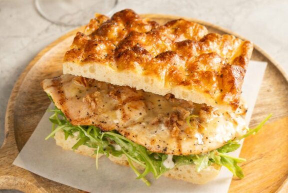 Sourdough focaccia sandwich on a wooden tray with serviette.