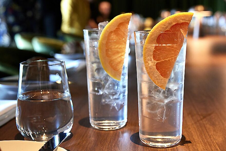 Two glasses of gin with a slice of orange as garnish.