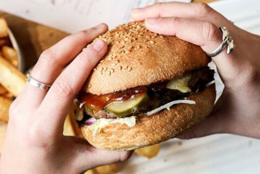 Hands holding a juicy burger.