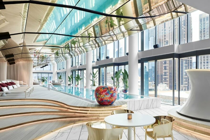 W hotel spa with curved glass ceiling and steps with views onto indoor swimming pool and terrace.