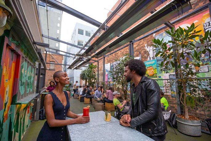 Two people enjoying drinks in a covered laneway bar.