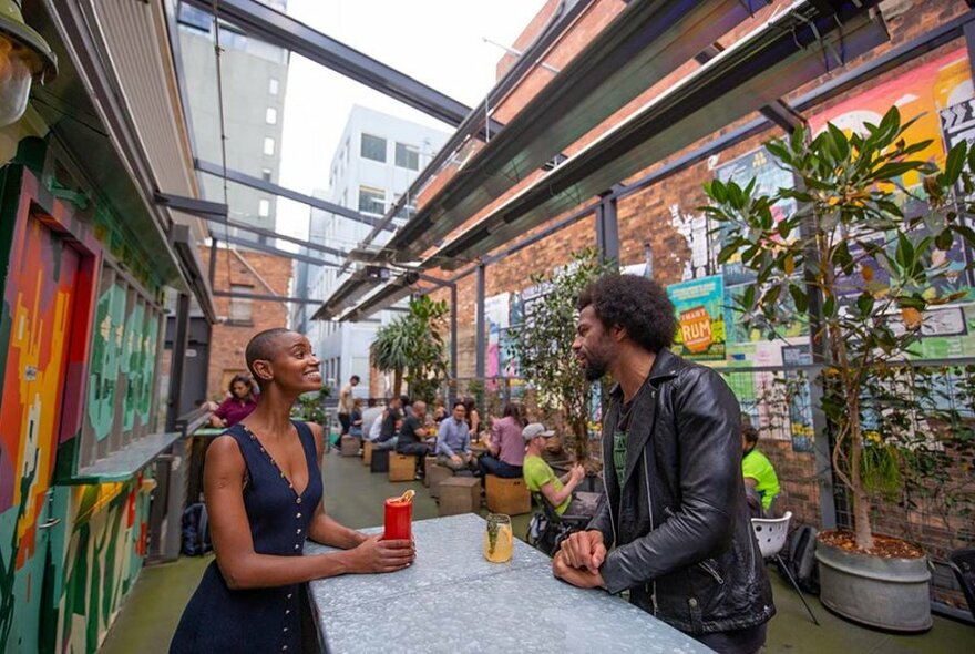 Two people enjoying drinks in a covered laneway bar.