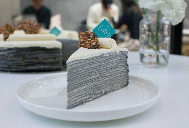 A grey crepe cake served on a white plate
