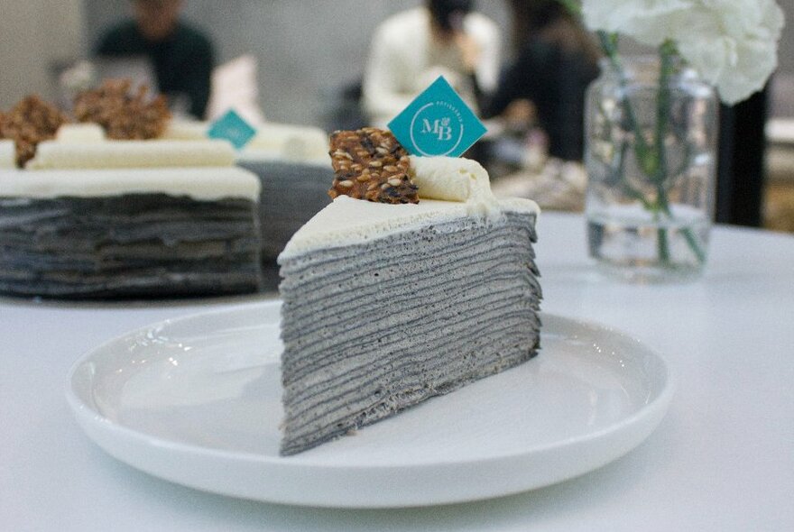 A grey crepe cake served on a white plate