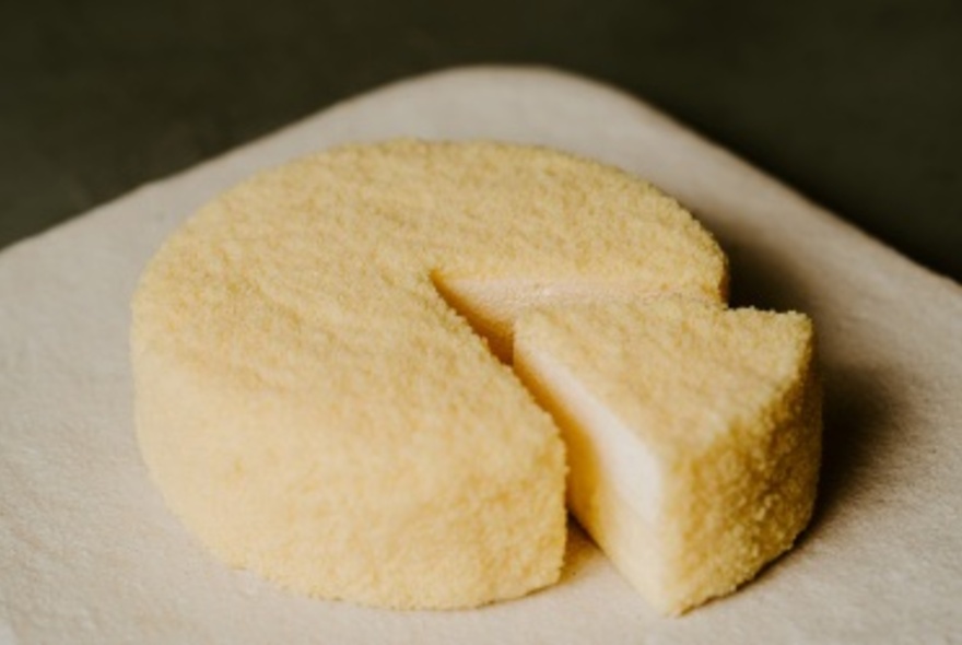 A round cheesecake with a triangular shaped slice cut out of it.