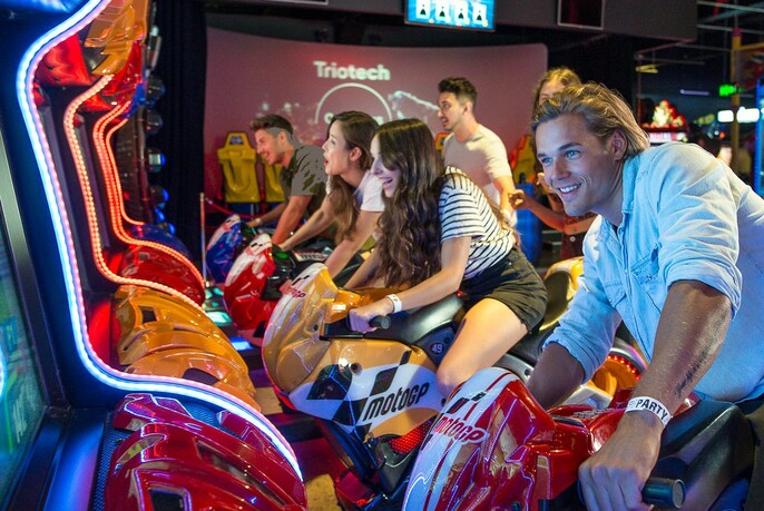People laughing and having fun on MotoGP arcade games.