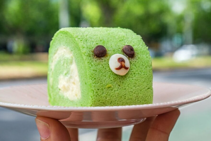 A green cake with a little cartoon bear face