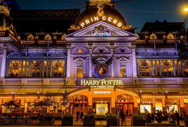 Exterior of the Princess Theatre, lit up by night, with signage for 'Harry Potter and the Cursed Child'.