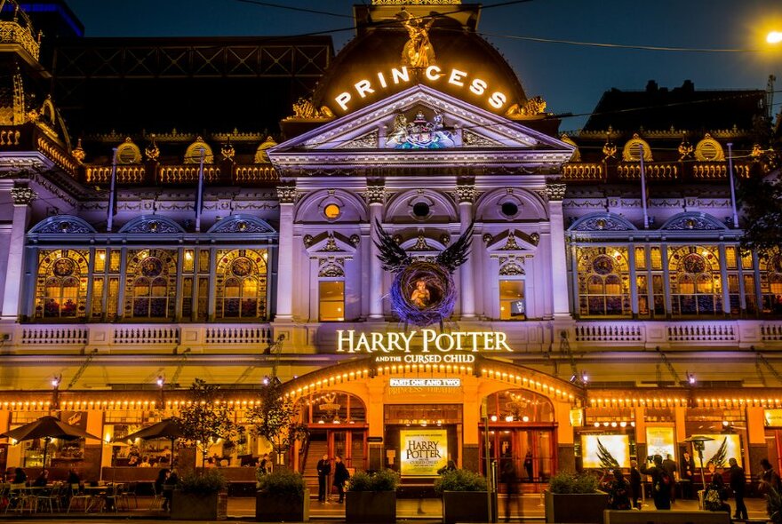 Exterior of the Princess Theatre, lit up by night, with signage for 'Harry Potter and the Cursed Child'.