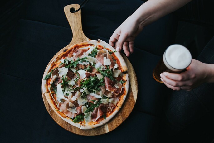 Pizza on a wooden paddle and a glass of beer.