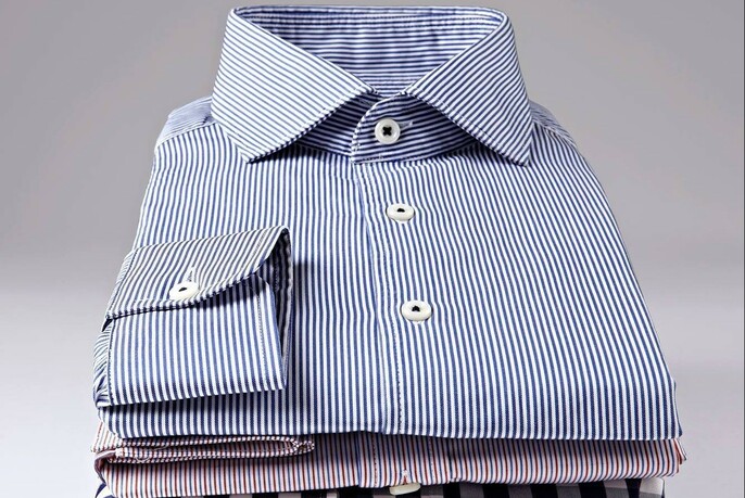 A pile of neatly folded buttoned shirts.