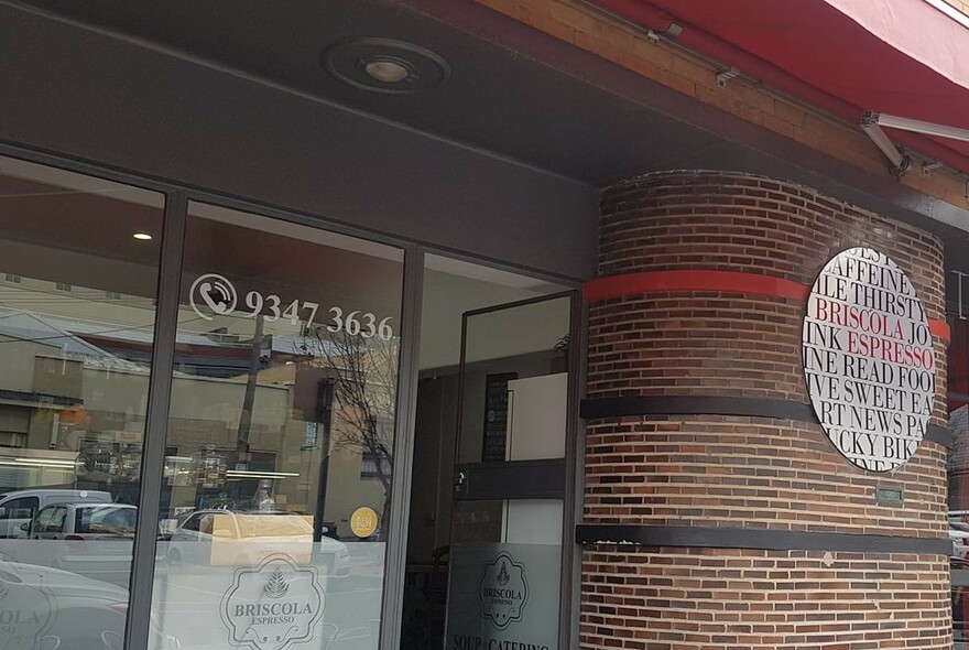 Cafe exterior with windows and brick pillar with signage.