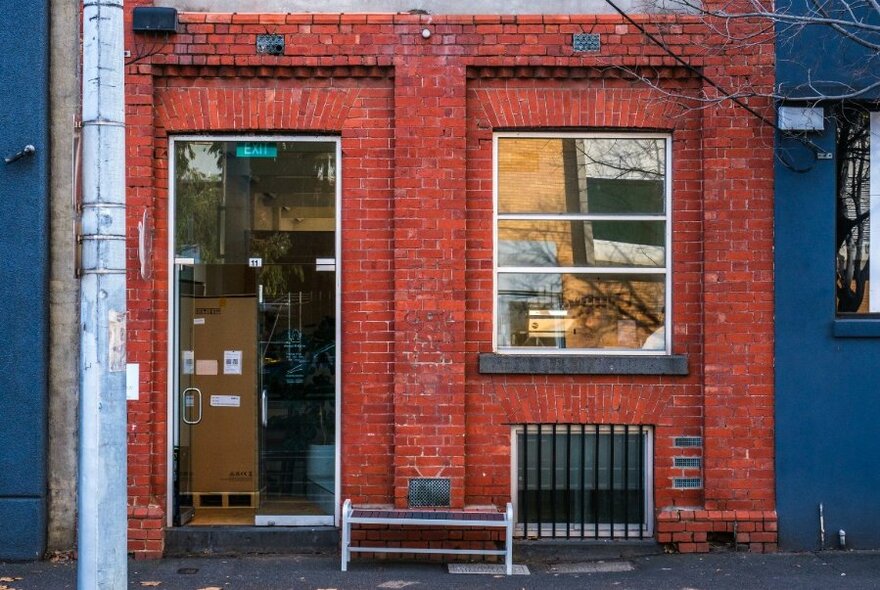 Red brick exterior of a cafe, featuring an open door and a square front window.