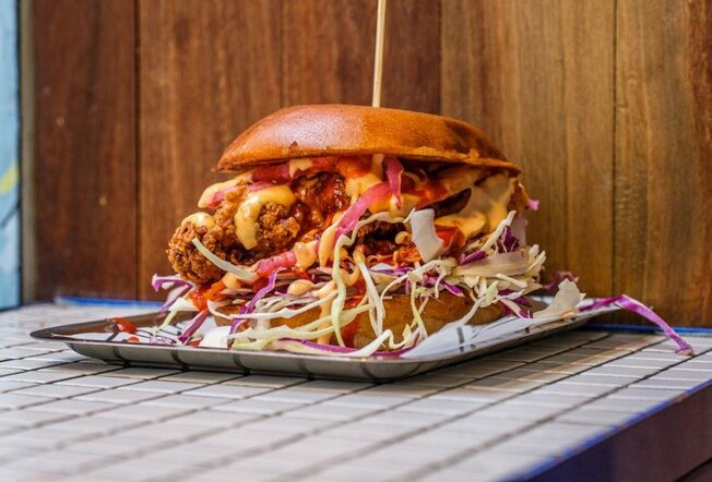 A large burger filled with fried chicken and slaw