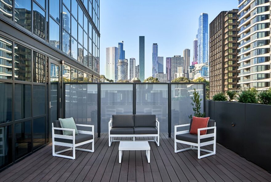 The deck at the Courtyard Melbourne hotel with outdoor furniture and city skyline views.
