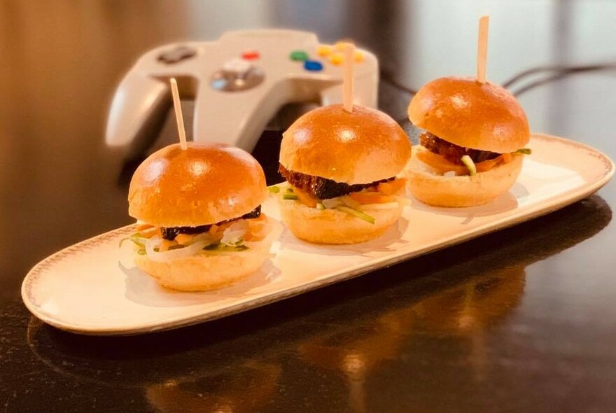 Three mini-hamburgers or sliders arranged on a plate. 
