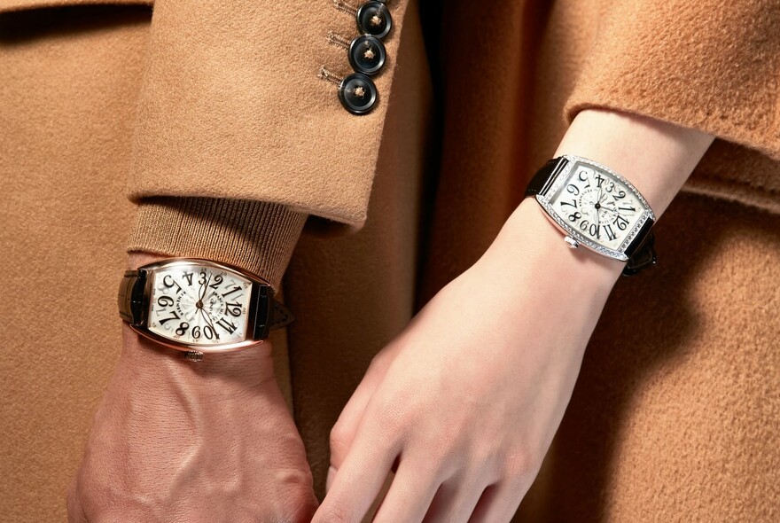 Male and female hands with matching wristwatches on leather straps.