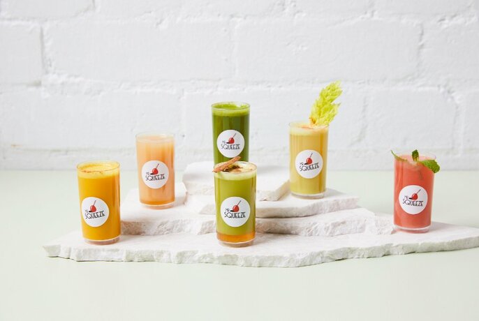Selection of fresh pressed juices on a white table.
