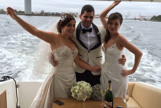 Bride, groom, and bridesmaid posing for photo at the back of the boat.