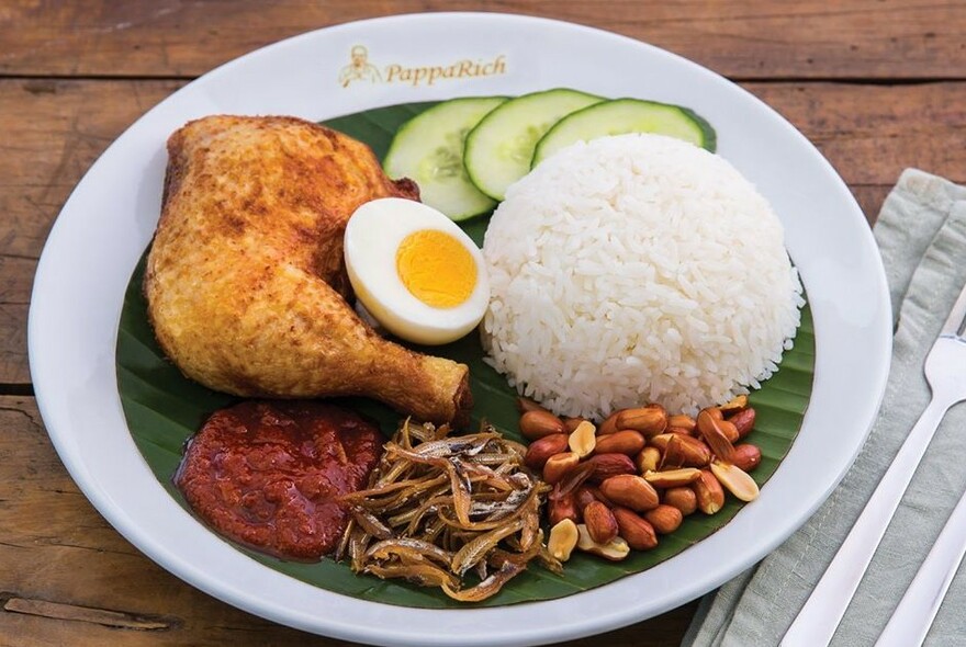 White plate with quarter chicken, rice, egg and peanuts.