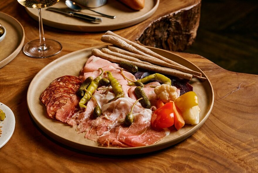 A charcuterie plate with sliced meats and grissini.