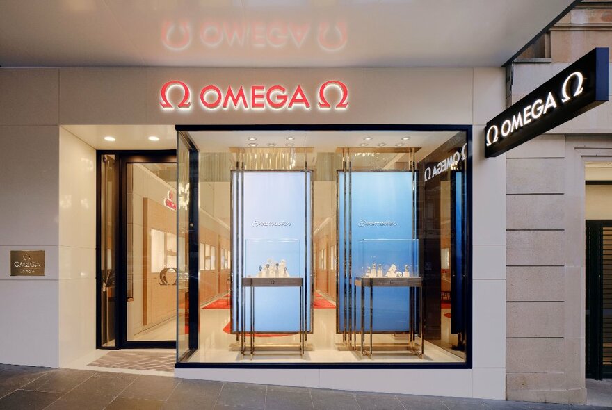 The exterior of an Omega store, with two small tables in the window. 