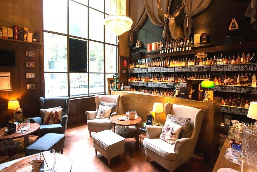 Inside The Whisky Boutique with armchairs and a bar in the background. 