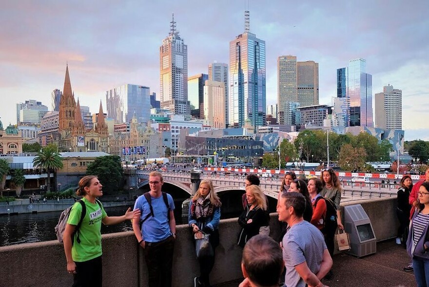 Tour guide talking to a crowd of people with Melbourne city skyline in the background.