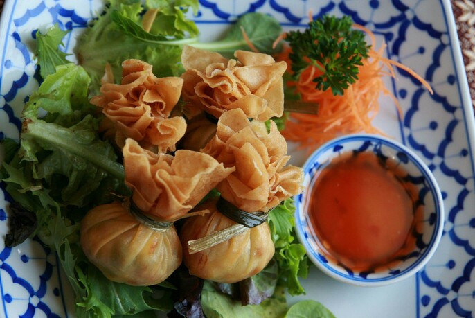 Blue and white dish with wantons, salad and sauce in a bowl.