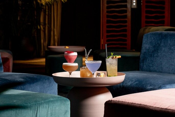 An array of cocktails on low table in centre of plush lounge chairs.