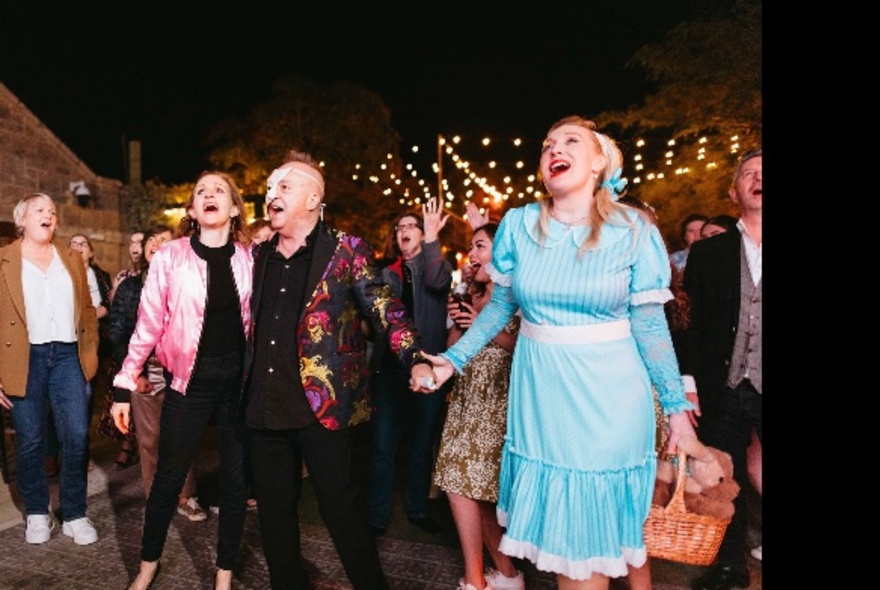 A group of people singing together in an open air outdoor space, some in costumes.