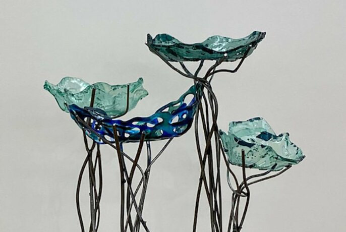 Free standing sculpture comprised of pieces of moulded glass balanced on metal sticks, vaguely resembling flowers on stalks.