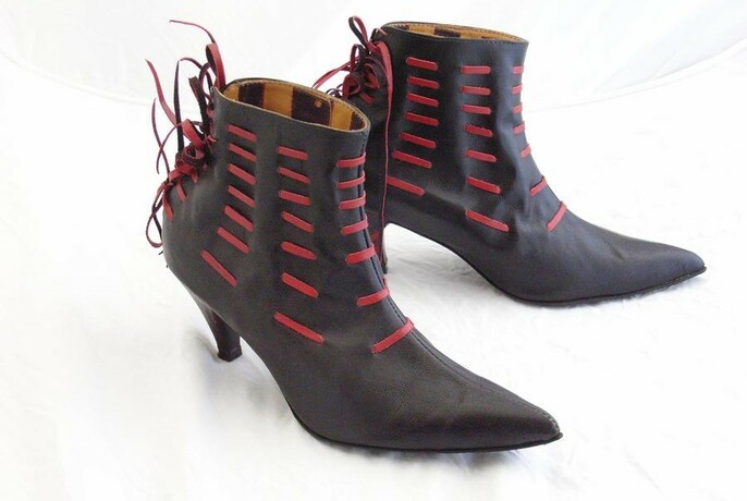 Pair of black leather ankle-length boots with red leather strips threaded through.