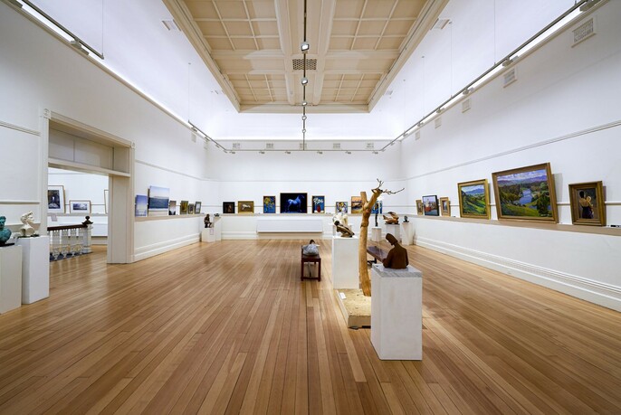 White gallery space with paintings on the walls.