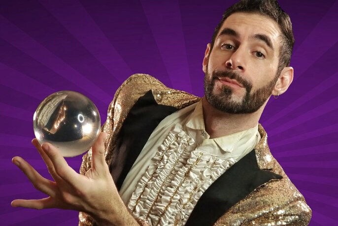 A man dressed in a glittery jacket and ruffled shirt holds a crystal ball against a purple background. 