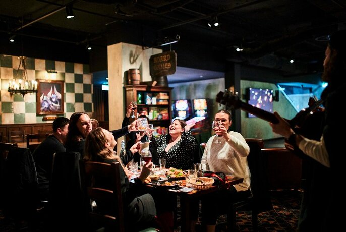 A table of laughing trivia players at a table laden with food and drinks.