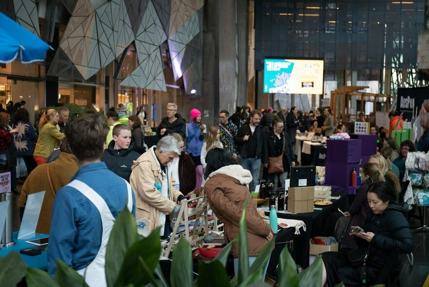 Crowds of people browsing market stalls at the Atrium covered plaza at Fed Square.