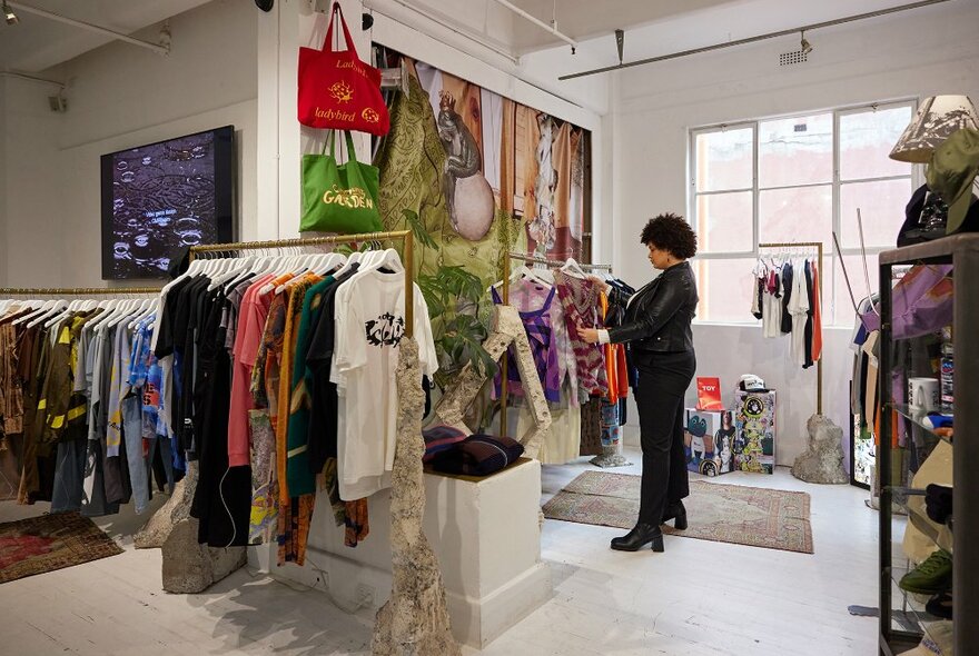 A woman looking at colourful clothing in a quirky streetwear store.