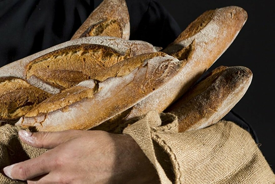 Hands holding a handful of baguette in hessian.