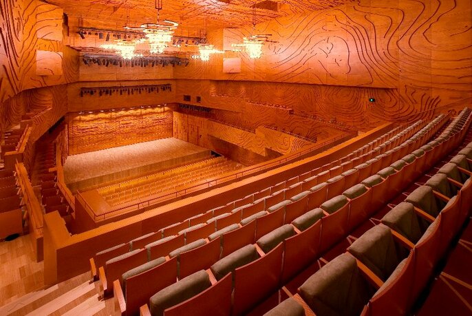 Long view of small, wooden auditorium, warm lighting.