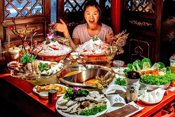 Woman looking amazed at a table loaded with plates of food.