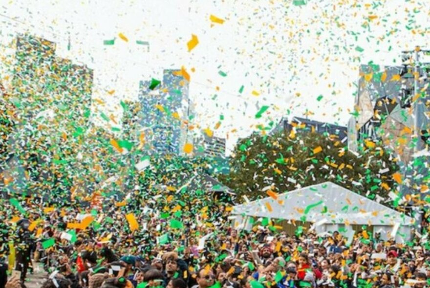 Crowds celebrating under green and yellow confetti.