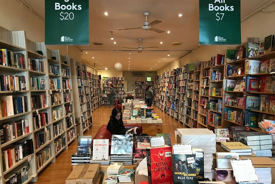 Inside of book shop showing shelves and tables of books for sale.