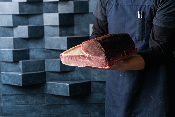 Chef holding a large cut of tuna.