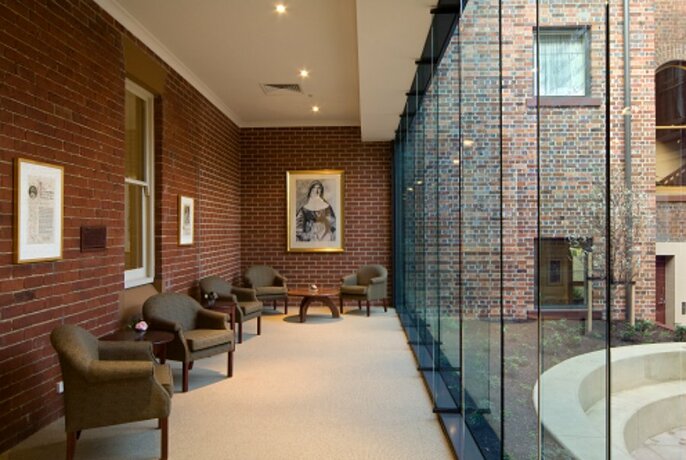 Internal corridor with floor to ceiling glass windows at right, looking onto courtyard.