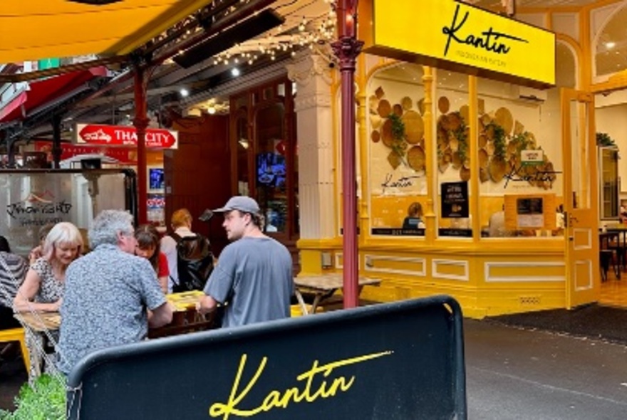 Yellow exterior of Kantin restaurant on Lygon Street with people seated at outdoor tables.