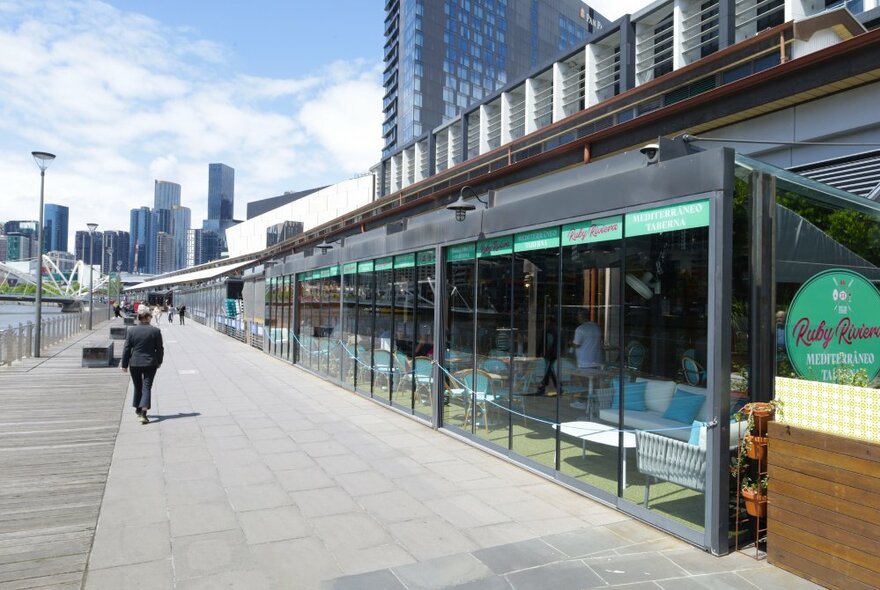 The exterior of a restaurant on south wharf with large glass windows looking out onto the wharf promenade and Yarra River.
