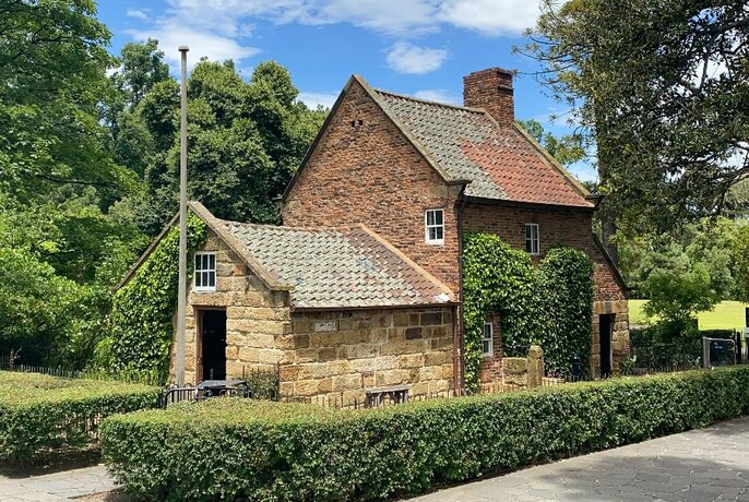 Historic Cooks' Cottage stone English building with ivy and hedges in Fitzroy Gardens.