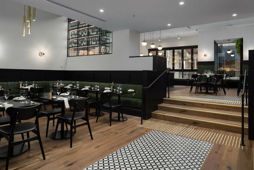 A chic restaurant interior with two levels and black dining tables and chairs