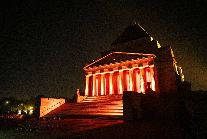 Melbourne's Shrine of Remembrance against a dark sky at dawn, with a soft warm spotlight on the portico columns.